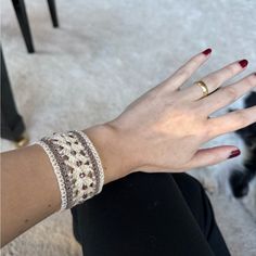 a woman's hand with two bracelets on it and a cat in the background