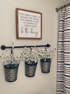 three metal buckets with flowers in them hanging on a wall next to a striped shower curtain