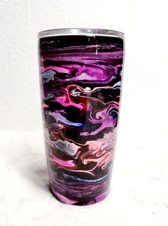 a purple and black glass sitting on top of a white table