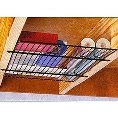 a metal basket filled with books on top of a wooden shelf