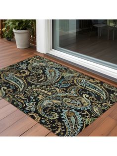 a black rug with blue and green designs on the floor in front of a glass door