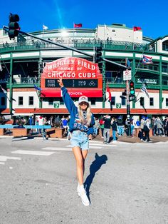 a woman is running across the street in front of wrigley field