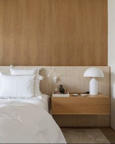 a white bed sitting next to a wooden headboard on top of a nightstand in a bedroom