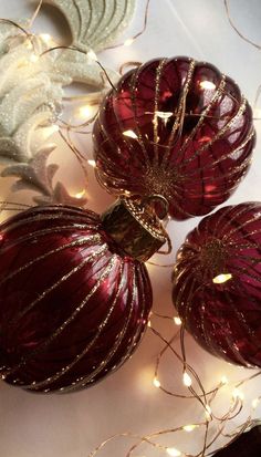 three shiny red ornaments with lights on them