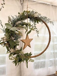 a wreath hanging from the ceiling with greenery and star decoration on it's side