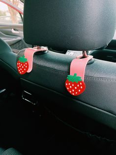 two strawberries are attached to the front seat of a car, with pink straps