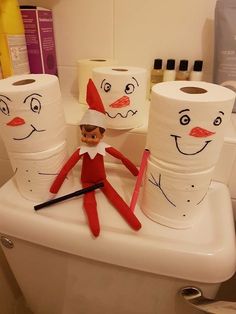 an elf is sitting on the toilet in front of several rolls of toilet paper with faces