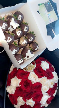 a box filled with chocolate covered strawberries next to a bouquet of red and white roses