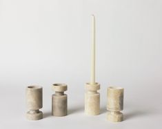 three candles and two vases on a white surface