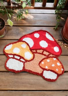 two mushroom rugs sitting on top of a wooden table next to a potted plant