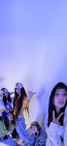 four young women posing for the camera in front of a white wall with blue lights