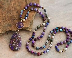 "Approx. 34\" L. Pendant size: 1.2\"x3\" Color, size, pattern may vary. Elevate your style with our enchanting Purple Sea Sediment Imperial Jasper Necklace, featuring a substantial stone pendant for a bold and distinctive look. Meticulously handcrafted, this necklace is not just a stunning accessory but also a symbol of stability and healing. The large Purple Sea Sediment Imperial Jasper pendant takes center stage, displaying a mesmerizing blend of deep purples and rich blues. Known for its stabilizing energy, this gemstone promotes a sense of calm and balance. The necklace goes beyond mere fashion, offering a connection to the earth's energies and a shield of healing crystal protection. Measuring approximately 34 inches, the knotted design showcases the natural beauty of Purple Sea Sedime Multicolor Jasper Spiritual Necklace, Spiritual Multicolor Jasper Necklaces, Multicolor Jasper Necklace For Gift, Crystal Protection Necklace, Crystal Protection, Purple Sea, Imperial Jasper, Jasper Necklace, Protection Necklace