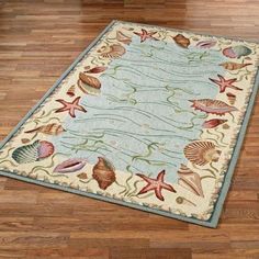 a rug with seashells and starfish on it in the middle of a wooden floor