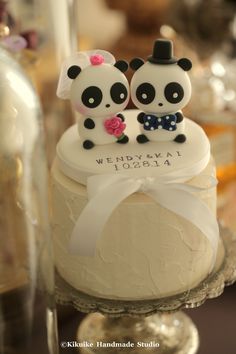 two panda bears sitting on top of a wedding cake