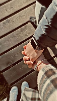 two people holding hands while sitting on a bench