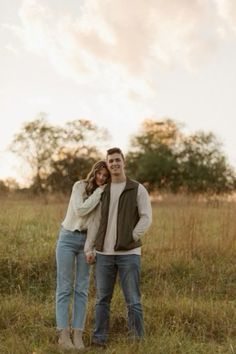 a man and woman are standing in the grass