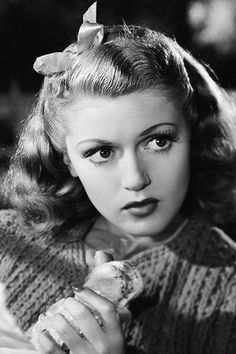 an old black and white photo of a woman holding a piece of food in her hand