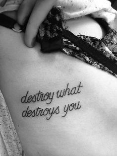 a woman with a tattoo that says destroy what destroys you on her back side