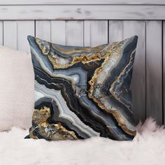 a black and gold marble pillow sitting on top of a white furnishing next to a