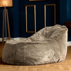 a bean bag chair sitting on top of a hard wood floor next to a lamp