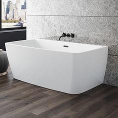 a large white bathtub sitting on top of a wooden floor next to a window