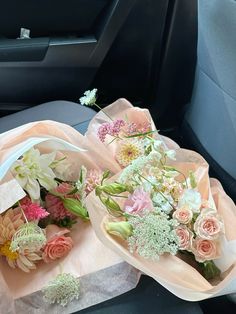 two bouquets of flowers sit in the back seat of a car, next to each other