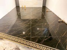 a bathroom with marble flooring and gold trim around the shower stall door, which is being installed