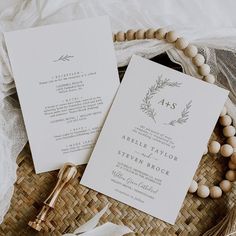 the wedding stationery is laid out on a wicker basket with beads and tassels