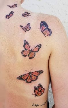 the back of a man's chest with many butterflies on his left shoulder and right arm