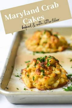 three crab cakes on a baking sheet with parsley sprinkled on top, ready to be eaten