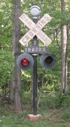 a railroad crossing sign with traffic lights in the foreground and trees in the background