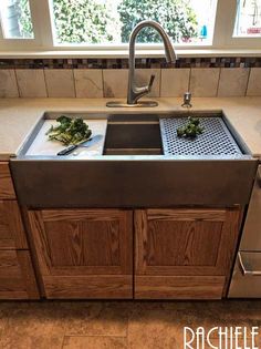 a stainless steel sink in a kitchen with wooden cabinets and tile flooring on the walls