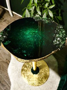 a green and gold table sitting on top of a white rug next to a potted plant