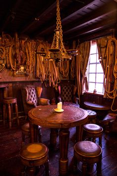 an old fashioned dining room with rope hanging from the ceiling and wooden chairs around it