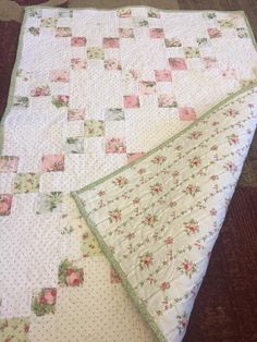 a white quilt with pink and green flowers on it