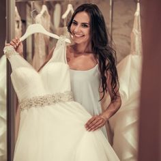 a woman is holding up a wedding dress