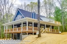 a large blue house sitting on top of a dirt hill in front of some trees