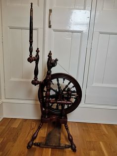 an old spinning wheel on the floor in front of a white door with wooden floors