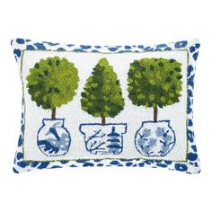 a blue and white pillow with three trees on the front, two vases in the middle