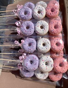 there are many donuts with pink and white frosting on them in the box