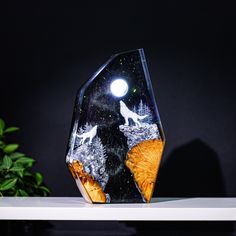 a glass sculpture with an image of two wolfs on it's face and the moon in the background