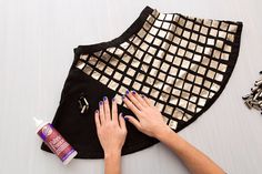 a woman's hands on top of a black and gold piece of cloth next to nail polish