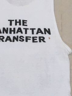 "1970s band tanktop shirt Hanes, cotton, white ribbed The Manhattan Transfer black print Atlantic Records symbol at lower right of image front/back image good vintage condition, light wear light stains, light cracking label size M, see below measures, lying flat, chest-12\" unstretched to 19\" stretched length-26\"" Stretch Cotton Vest With Letter Print, Retro Fitted Crew Neck Tank Top, Fitted Retro Crew Neck Tank Top, Retro White Tank Top For Streetwear, Retro Stretch Tank Top With Graphic Print, White Vintage Stretch Top, Fitted Cotton Muscle Tee With Graphic Print, Fitted White Cotton Muscle Tee, 90s White Tank Top For Streetwear