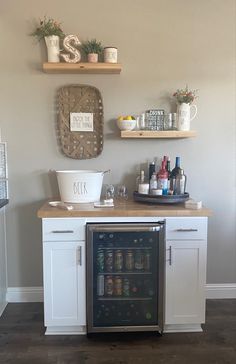 a small kitchen with white cabinets and open shelving on the wall next to an ice chest