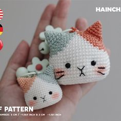 two small crocheted cats sitting on top of each other in someone's hand