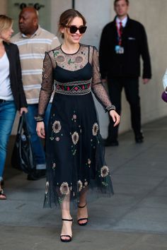 a woman walking down the street in a black dress