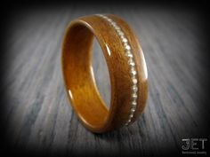 a wooden ring with pearls inlayed to it sitting on a wood table top