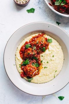 a white bowl filled with meatballs covered in sauce and garnished with parsley