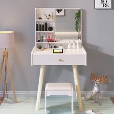 a desk with a mirror, lamp and deer figurine on the floor next to it