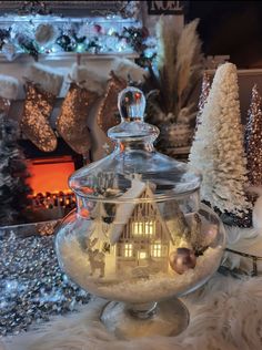 a glass bowl filled with snow and a house in the center surrounded by christmas trees